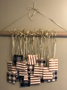 This image shows an example of the Advent Calendar Craft. Pouches of wrapping paper hang from a cardboard roll for persons to cut down as a countdown to Christmas. 